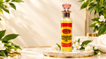 A bottle of Lily Arabian Whitening Oil stands on a round marble tray, surrounded by white flowers and green leaves against a warm cream background with soft shadows.